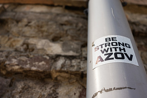 Sticker supporting Azov Brigade displayed on a metallic pipe against a brick wa, a Photo by AS photostudio