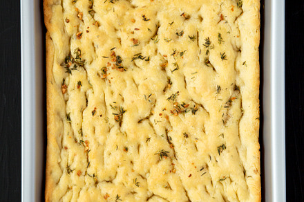 Home-baked Rosemary Garlic Focaccia Bread on baking tray on blac, a Food & Drink Photo by LiudmylaChuhunova