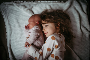 Young girl holding newborn sister, a Person Photo by HalfPoint