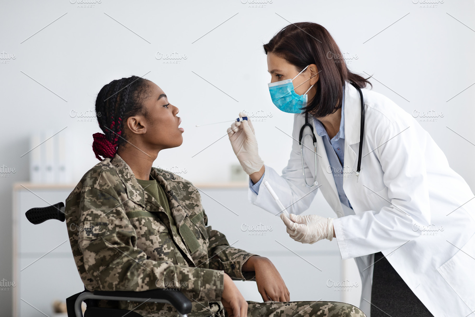 Female Doctor Making PCR Coronavirus Test To Black Military Woman In Wheelchair, a Photo by Prostock-Studio