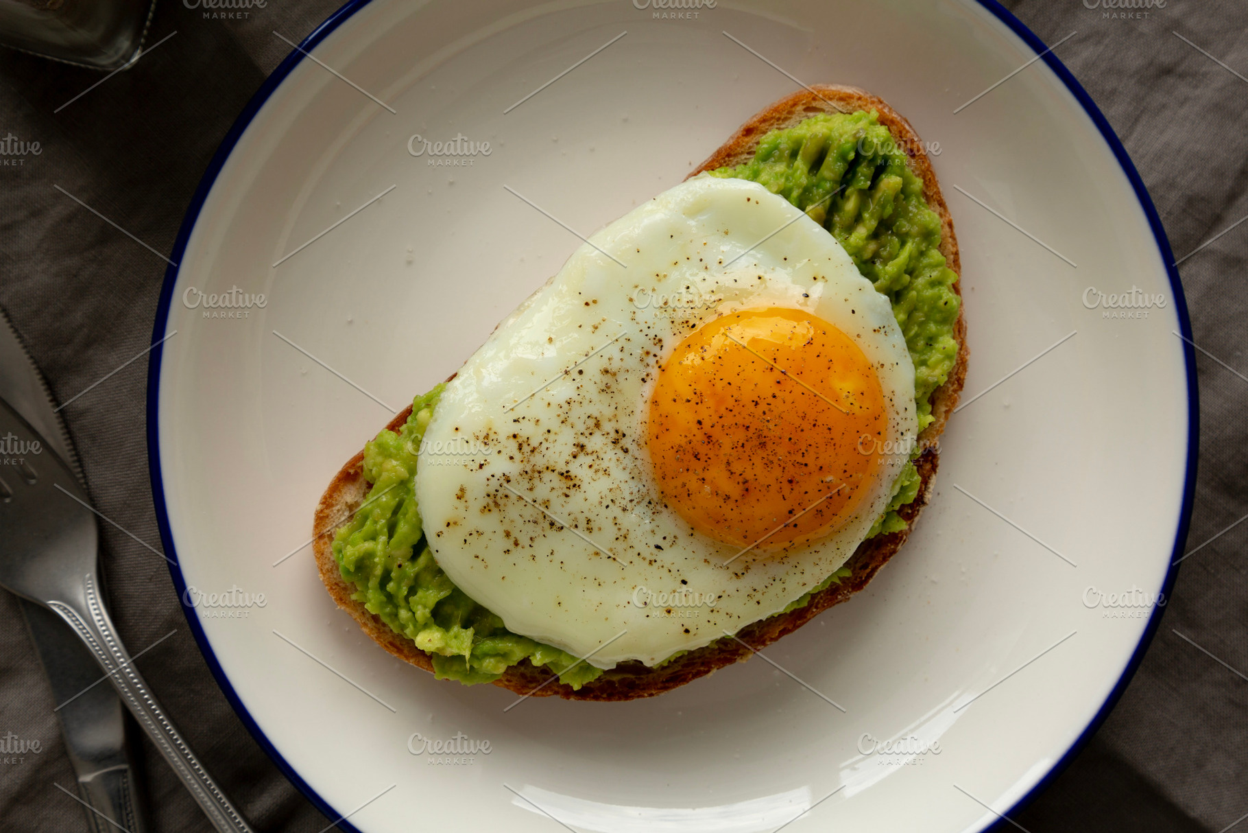 Homemade Avocado Toast with Egg on a Plate, top view., a Food & Drink Photo by LiudmylaChuhunova