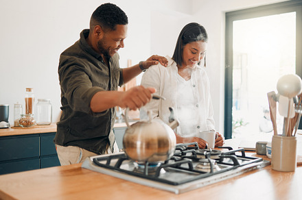 Loving couple having coffee or tea, relaxed and carefree while bonding in a kitchen at home. Caring husband being affectionate, talking and enjoying their relationship and quiet morning with his wife, a Photo by Peopleimages.com