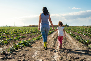 Woman farmer and little girl walking containing woman, child, and garden