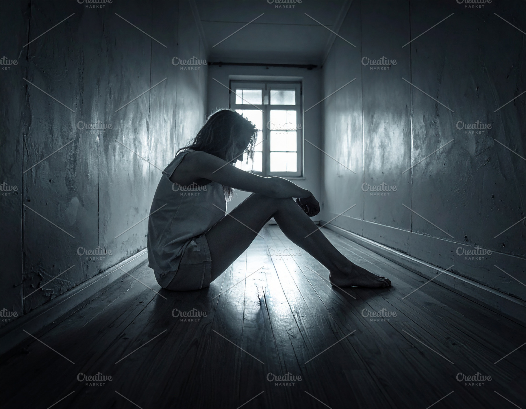 Sad woman sitting on floor in dark narrow hallway, a Person Photo by DanFLCreativo