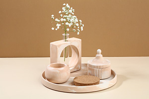 Modern DIY concrete home decor on beige background. Vase of flowers, cup, podiu