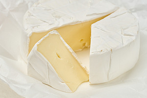 A round head of soft Camembert cheese with white mold, one trian, a Food & Drink Photo by ndanko