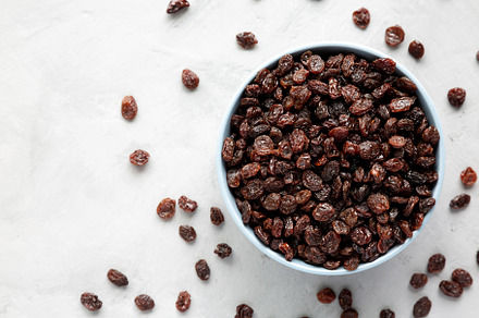 Dried Brown Raisins in a Bowl, top view. Flat lay, overhead, fro, a Food & Drink Photo by LiudmylaChuhunova