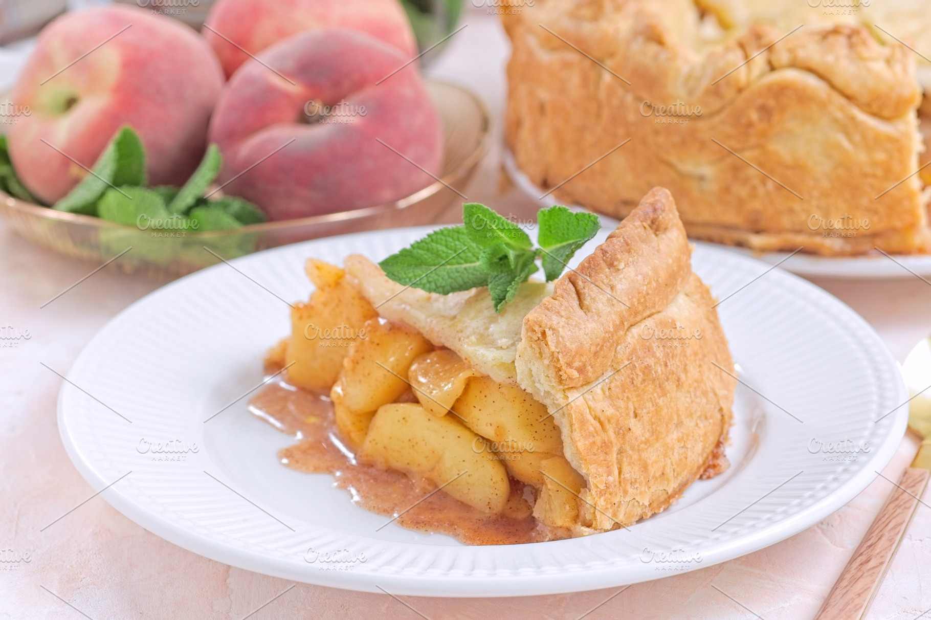 Old fashioned deep dish peach pie slice garnished with fresh mint, on white pla, a Food & Drink Photo by iuliia_n