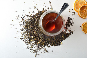 Detail black tea cup leaves scattered on a white table, a Food & Drink Photo by Davizro's Market