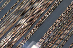 Closeup of multiple gold and rose gold chains displayed in a jewelry showcase, a Photo by AS photostudio