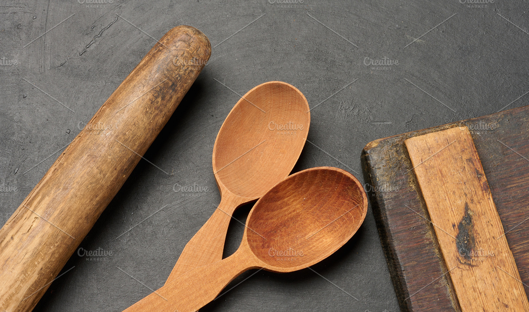 Wooden spoons, cutting board and rolling pin on a dark surface, a Food & Drink Photo by ndanko