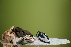 Iron and unfolded laundry on ironing board, a Photo by Alliance Images
