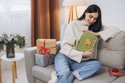 Beautiful happy woman unwrapping New Year or Christmas presents