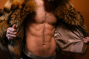 Muscular man wearing fur coat posing in studio, a Photo by karrastock