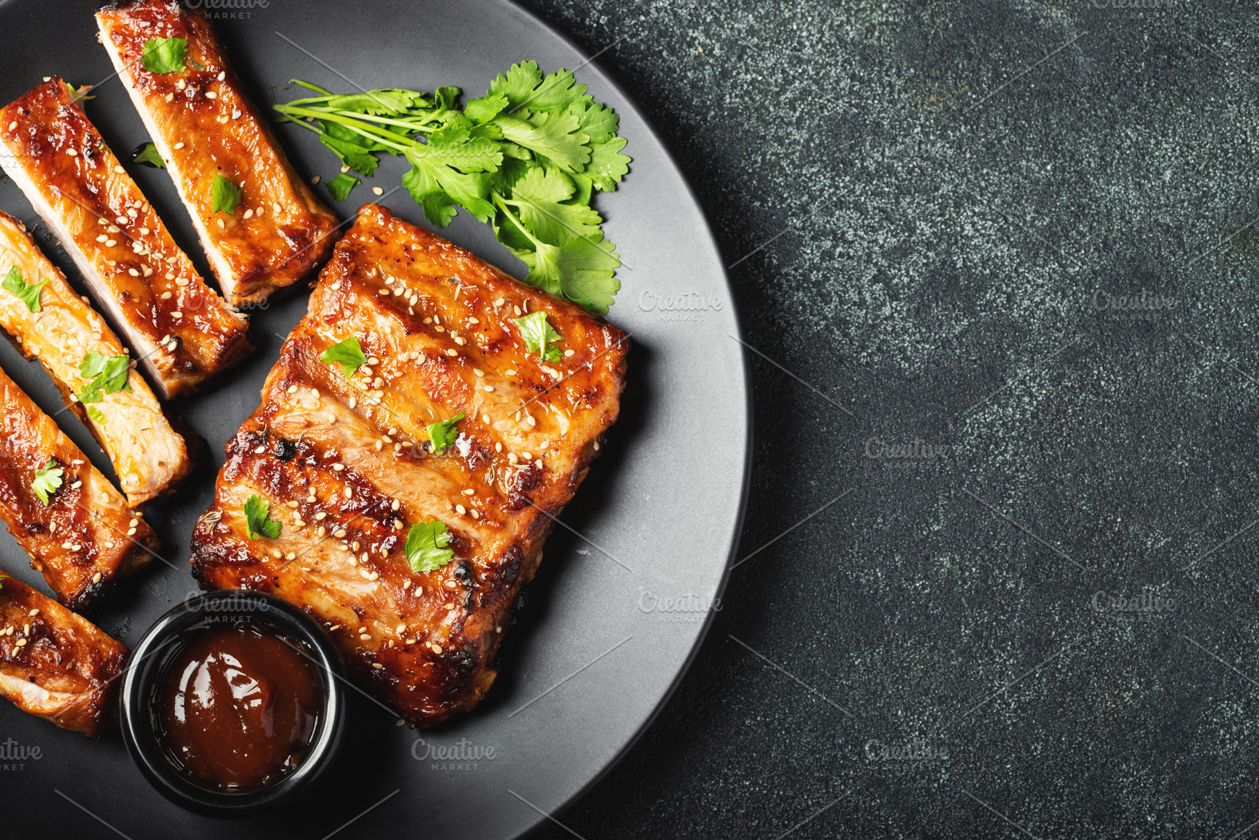 Hot grilled spare ribs from a summer BBQ served on a plate with sauce. Top view, a Food & Drink Photo by Budarinphoto