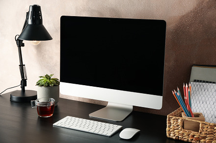 Workplace with computer, plant and lamp on wooden table. Light b, a Business Photo by AtlasStudio