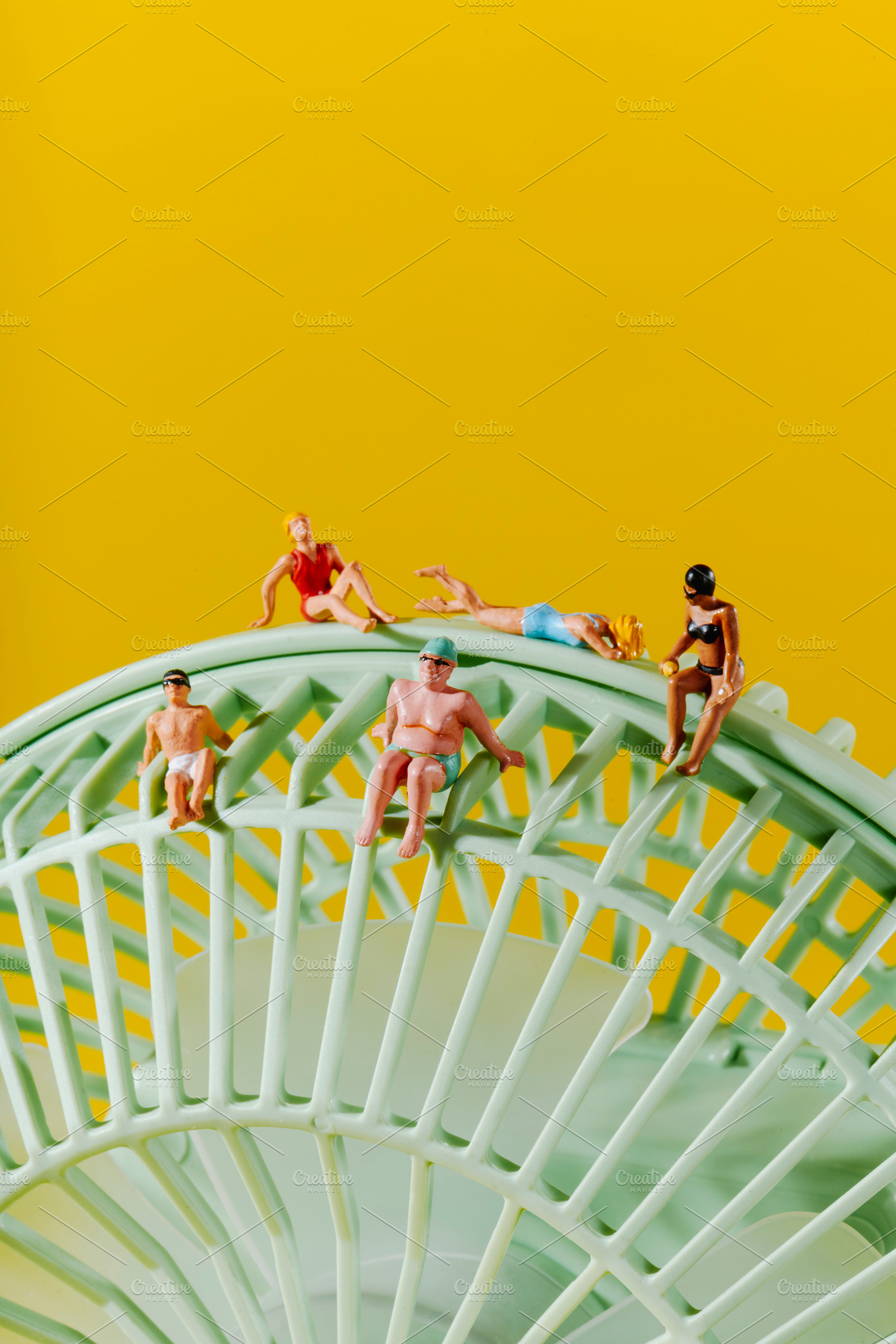 five miniature people in swimwear on a green fan, a Photo by Nito