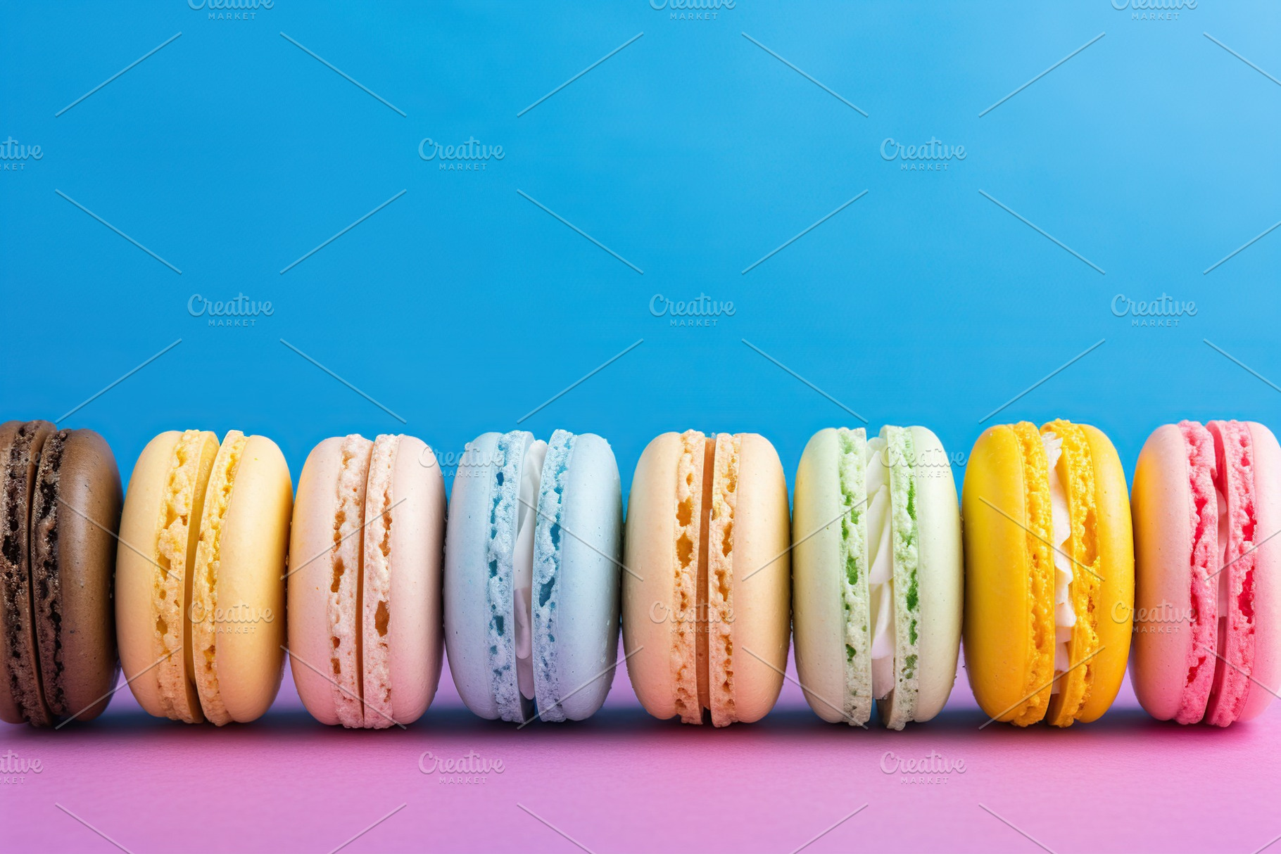 Colorful macarons dessert in a row on blue background, a Food & Drink Photo by AlyaAnd