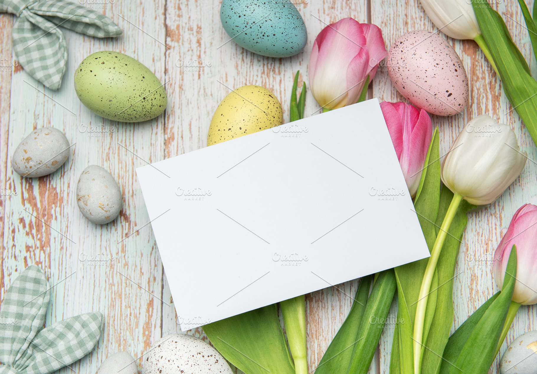 Easter eggs and tulips framing a blank card on rustic wooden bac, a Holiday Photo by Olena Rudo