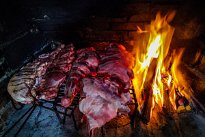 Raw meat sizzling on the grill beside an open fire, a Food & Drink Photo by DanFLCreativo