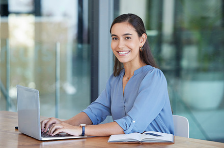 Business woman, portrait and typing on laptop at office desk, table and startup company. Happy young female, worker and computer technology for email, internet planning and professional seo research, a Photo by Peopleimages.com