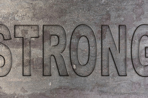 The word STRONG embossed on a textured metal surface, a Background Photo by ndanko
