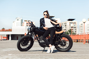 Biker girl sitting on vintage custom motorcycle containing moto, caferacer, a Transportation Photo by Aliaksei Kaponia