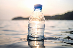 Plastic bottle floating in ocean water at sunset, a Nature Photo by GoodGoods