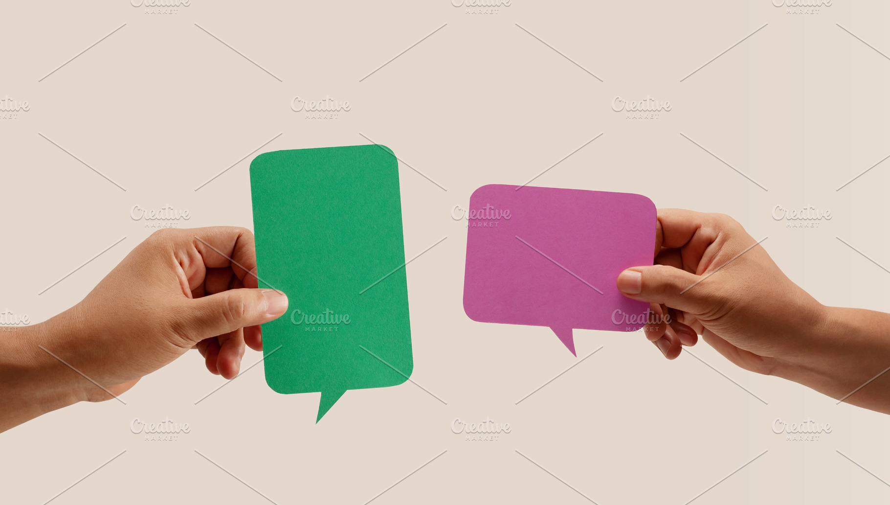 Two hands hold colorful blank speech bubbles over a neutral back, a Photo by salmon.black