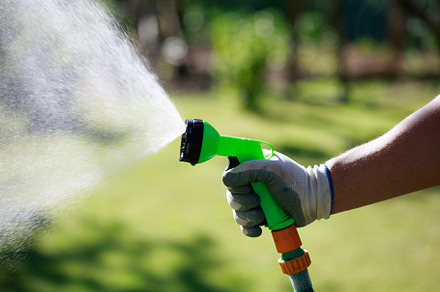 Gardener watering lawn with hose sprinkler. Hand with spray gun, close up view., a Nature Photo by photoguns