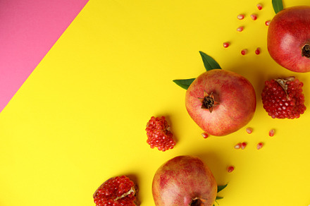 Ripe pomegranate, leaves and seeds on yellow background, a Food & Drink Photo by AtlasStudio PRO