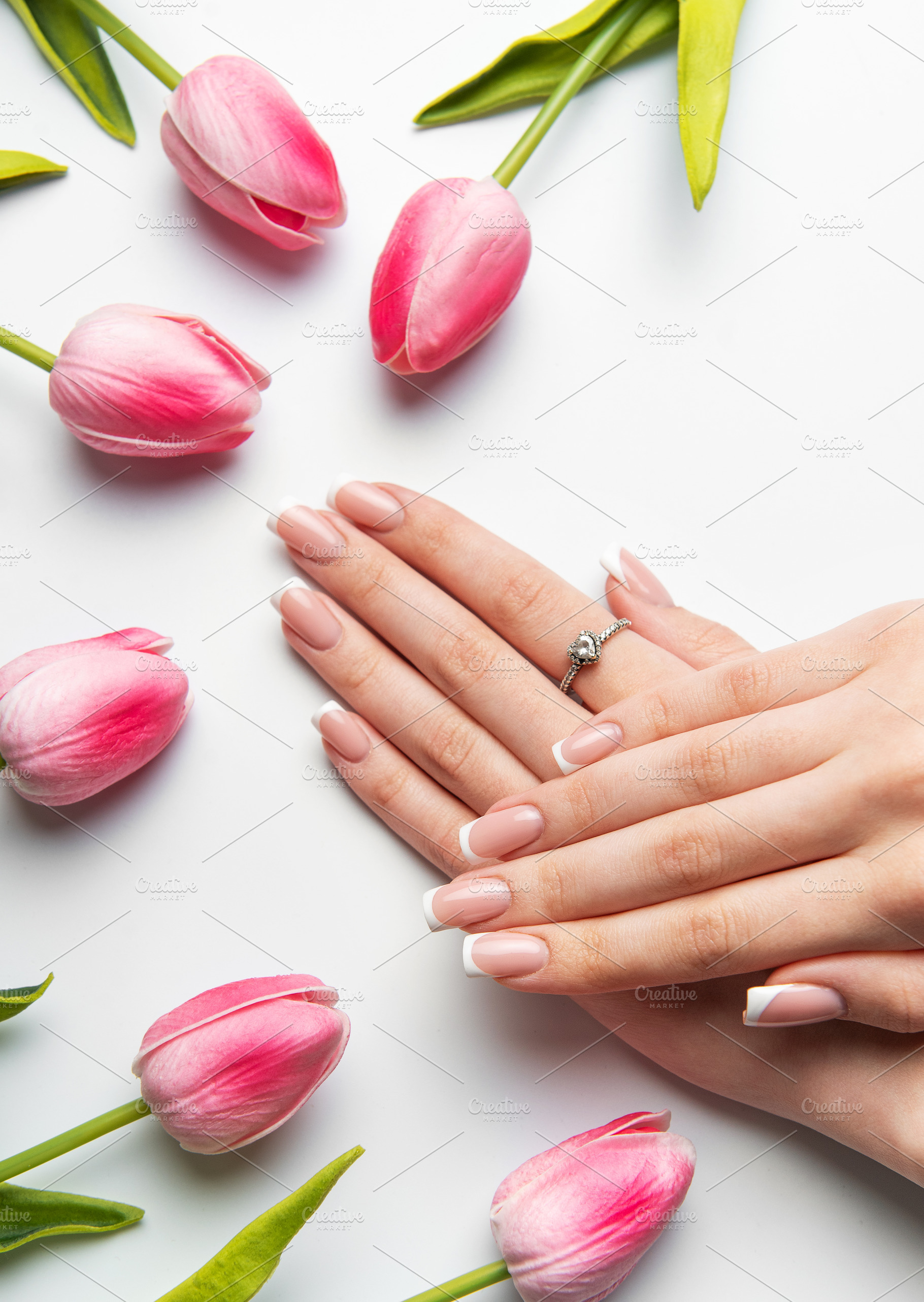 Woman showing french manicure near pink tulips on white backgrou, a Beauty & Fashion Photo by Olena Rudo