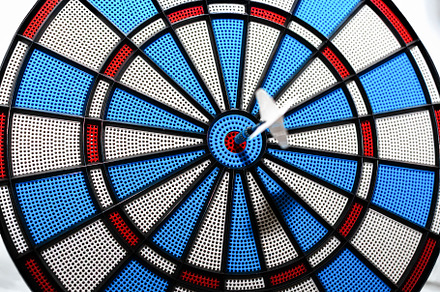 White dart striking the bullseye on a vibrant plastic dartboard