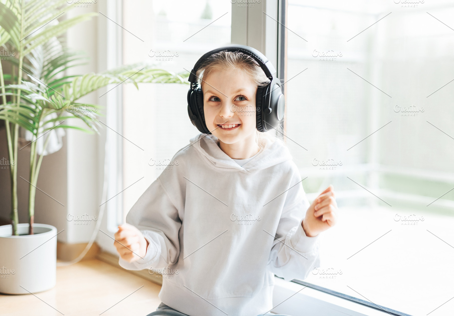Cute little girl listening to music in headphones, a Person Photo by Olena Rudo