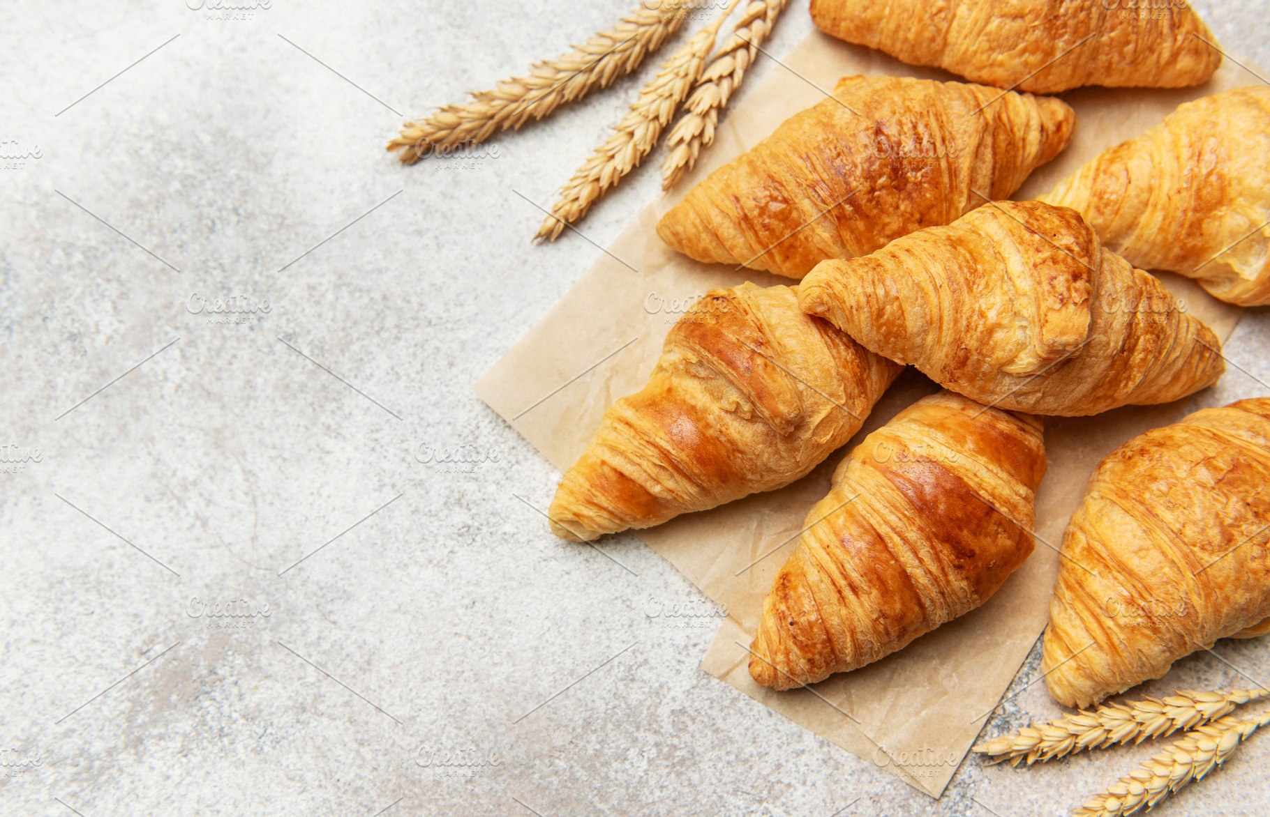 Freshly baked croissants with wheat on baking paper, a Food & Drink Photo by Olena Rudo