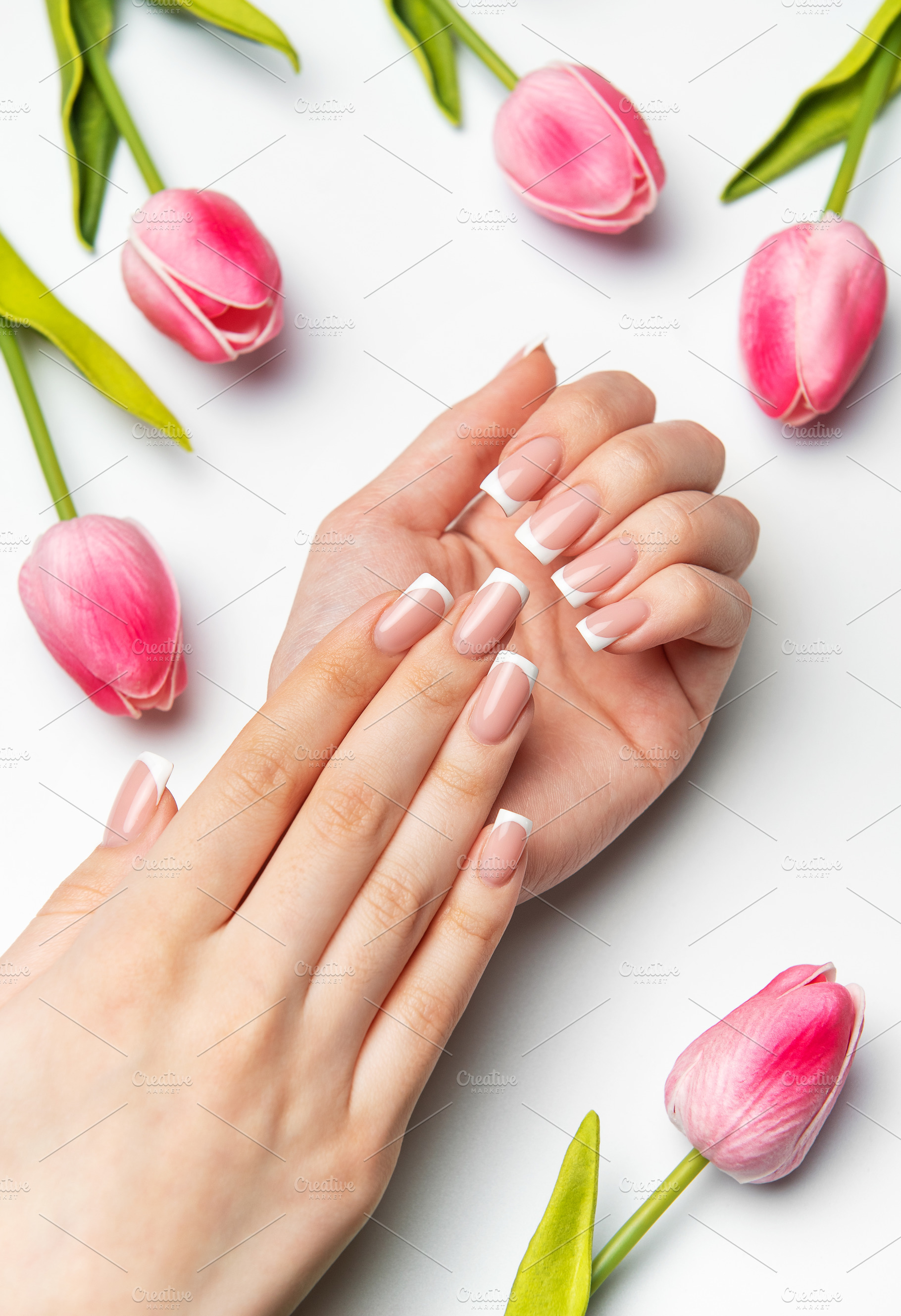 Woman showing french manicure near pink tulips on white backgrou, a Beauty & Fashion Photo by Olena Rudo