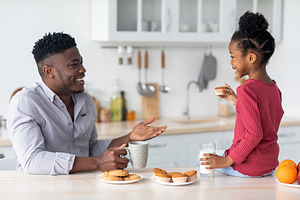 Friendly african american family chatting while having snack, a Photo by Prostock-Studio