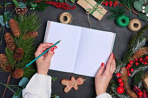 A woman sits at a table surrounded by Christmas decorations and, a Holiday Photo by ndanko