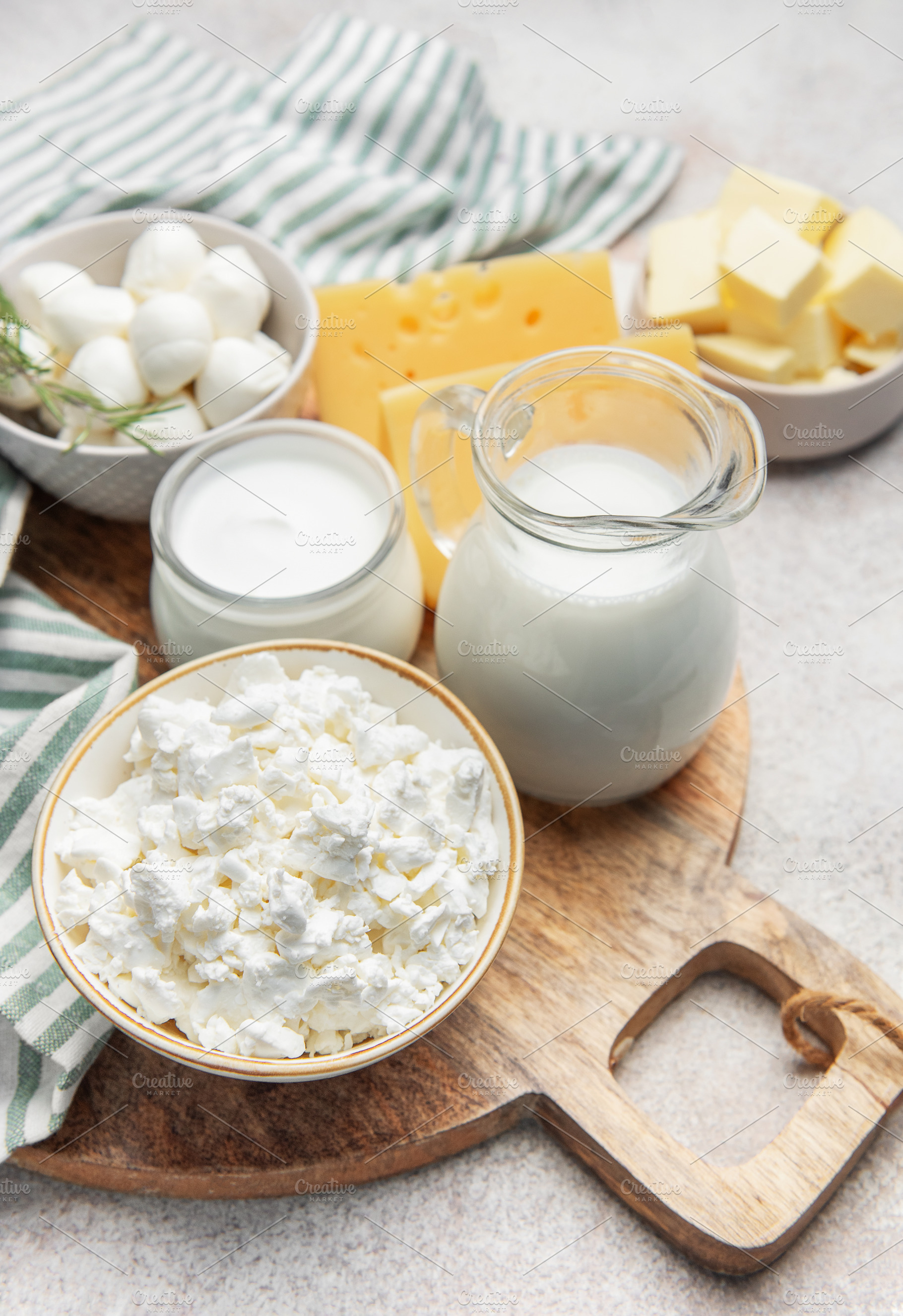 Assortment of fresh dairy products on wooden cutting board, a Food & Drink Photo by Olena Rudo