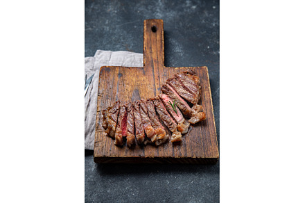 Fried strip loin steak on wooden, a Food & Drink Photo by LARISA BLINOVA