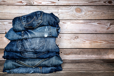Fashionable clothes pile of jeans on a wooden background containing jeans, a Beauty & Fashion Photo by OS