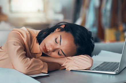 Tired woman suffering from burnout at work, sleeping at desk and napping after meeting a deadline in an office alone. Business woman and corporate professional resting, taking a break with laptop, a Photo by Peopleimages.com