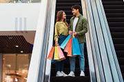 Couple Shopping Holding Bags Standing On Moving Stairs In Mall, a Photo by Prostock-Studio (Thumbnail 1 of 2)