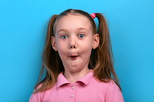 Funny close-up of a young girl in a pink shirt making a surprise, a Person Photo by Ales Munt