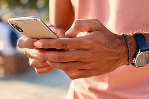 Young man focused on smartphone while standing outdoors during a sunny day, a Technology Photo by AlyaAnd