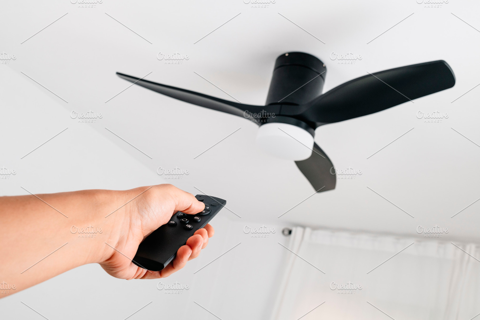 man operating a ceiling fan with remote control, a Photo by Nito
