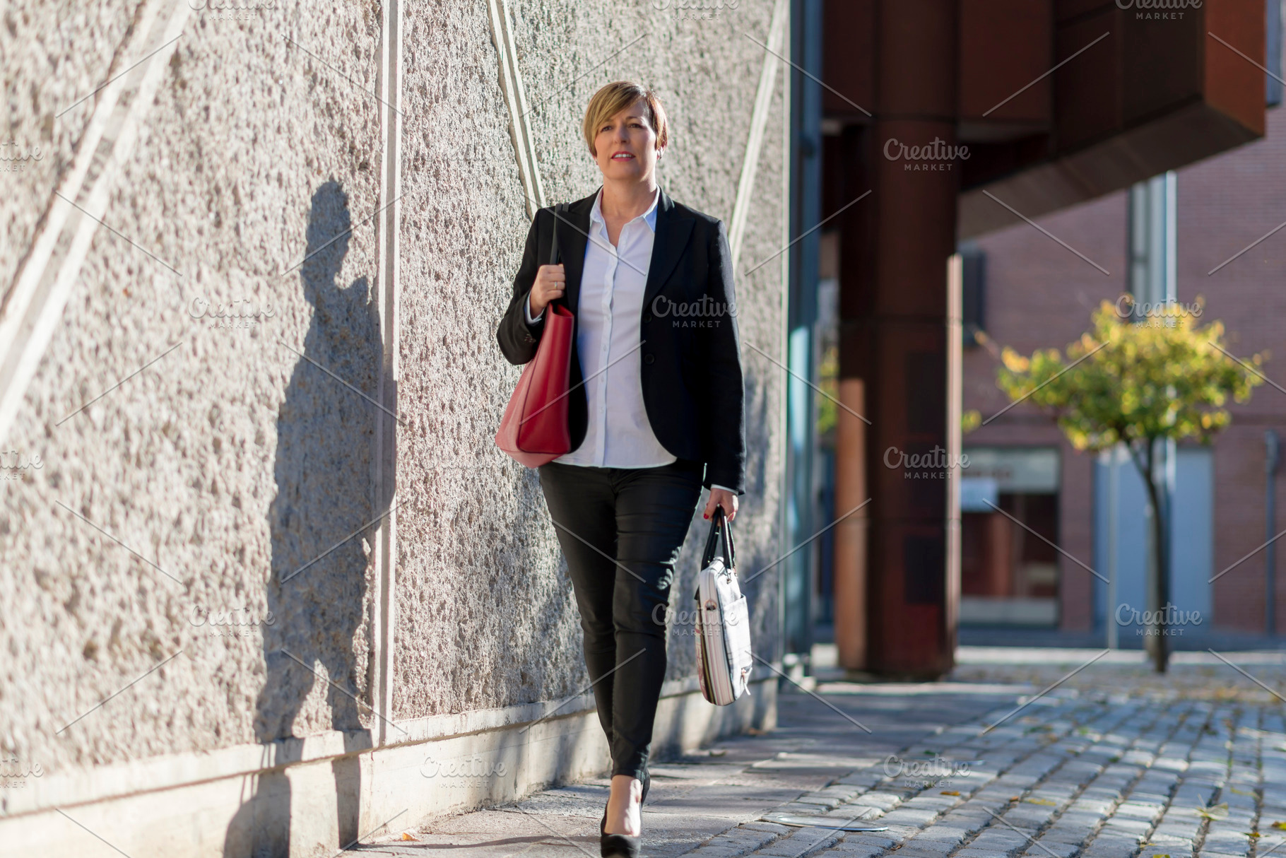 Businesswoman walking outdoors with handbags, a Photo by RF Images