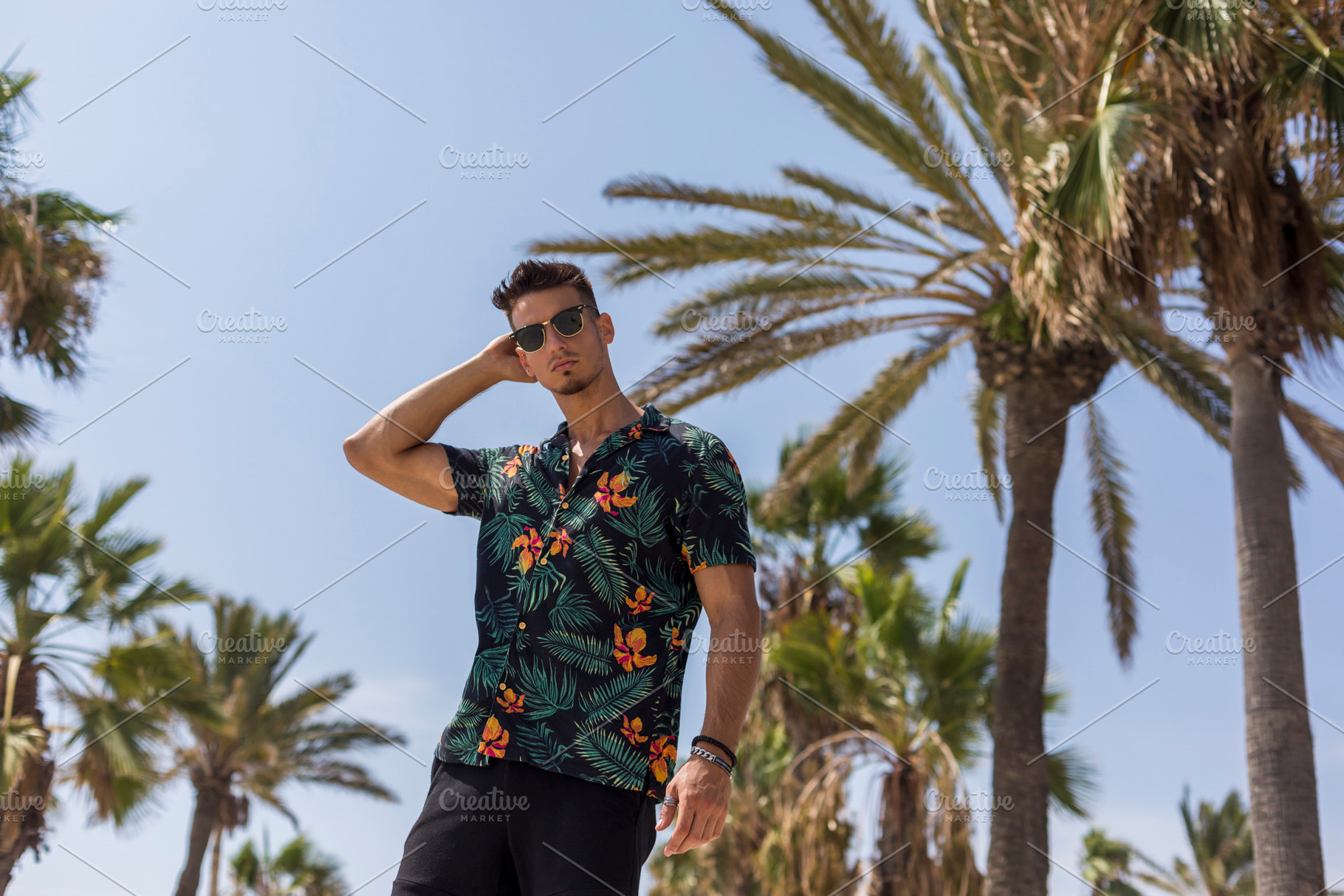 Young man in tropical shirt posing by palm trees, a Person Photo by RF Images