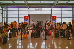 Crowded airport boarding area with travelers and luggage, a Transportation Photo by DanFLCreativo