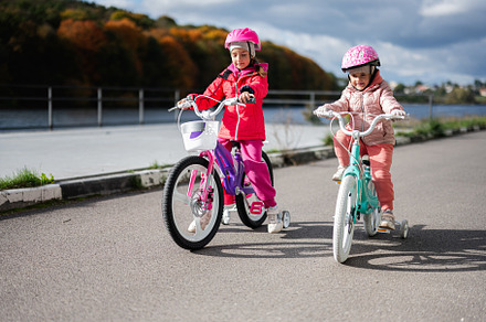 Two young children riding bikes on a scenic riverside path, a Person Photo by AS photostudio